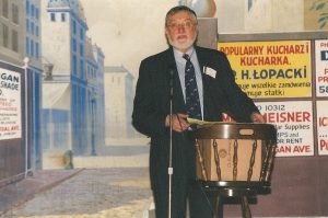 Thaddeus C. Radziłowski, Ph.D., presenting a lecture on the stage of the west side Dom Polski (May 5, 2015). The street scene backdrop is visible in the background.