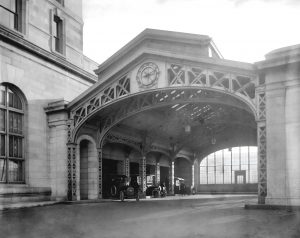 Michigan Central Station exterior with cars parked under archway, 1913