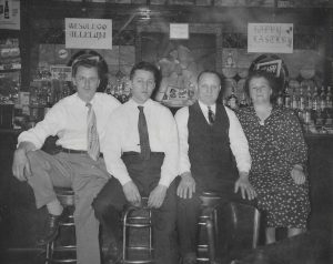Anthony (Tony), Walter, John, and Kathryn, at the bar inside Michno’s Café, ca. 1939, with WESOŁEGO ALLELUJA – HAPPY EASTER signs on the wall in the background.