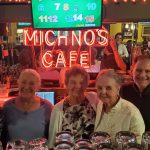 Ron Michno (second from right) in 2025 at Michno’s Café in Redford Township, with his wife of 52 years, She She Michno (far right). Also pictured, left to right, are Mary Ann, Theresa, Aurelia, and Loretta, all daughters of John W. and Stella L. (Michno) ZaydelThe original, bright neon Michno’s Café lighting from the Central Street Michno’s Café shines on behind the bar, paying homage to the enduring Michno’s legacy.